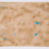 A piece of tan handmade paper with blue flecks on it