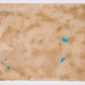 A piece of tan handmade paper with blue flecks on it