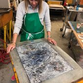 A woman looking down at her art piece