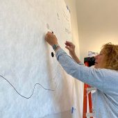 A woman putting Velcro circles on an art template