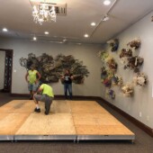 Installing the floor for Hello Sailor Two men and a woman setting up a floor platform in an art gallery.