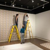 Installing the custom wallpaper Two women and a man hanging wallpaper