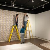 Installing the custom wallpaper Two women and a man hanging wallpaper