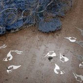 Blue paper in a net and silver cut outs on a floor