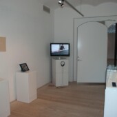 An art exhibit with pictures and a tv on pedestals