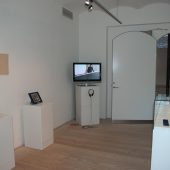 An art exhibit with pictures and a tv on pedestals