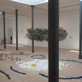 An art exhibit with mixed media art on the floor and wall