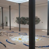 An art exhibit with mixed media art on the floor and wall